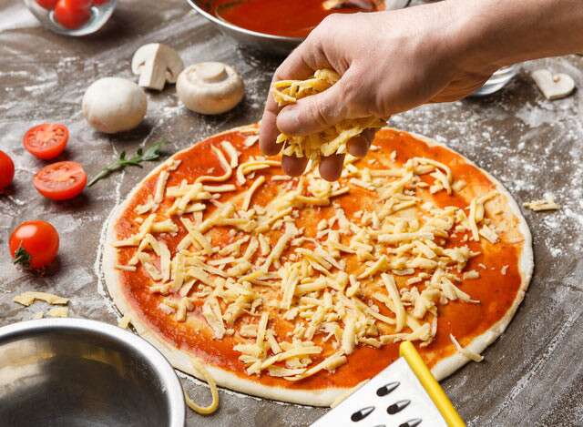 cheese spreading on pizza for baking
